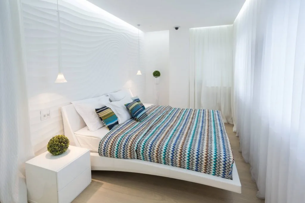 Потолок в маленькой спальне визуально приподнят с помощью подсветки